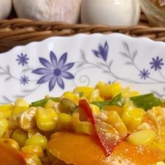 a white plate topped with corn and carrots on top of a table next to garlic