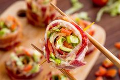 a wooden cutting board topped with lots of veggies and meat wrapped in bacon