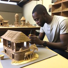 a man sitting at a table working on a model