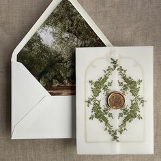 an envelope with a wax stamp on it and a card inside the envelope is decorated with green leaves