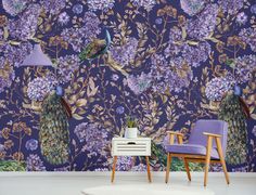 a purple wallpaper with peacocks and flowers on it, next to a chair