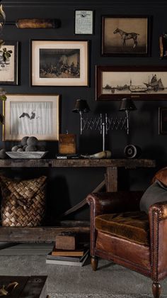 a living room filled with furniture and framed pictures on the wall above an old leather chair