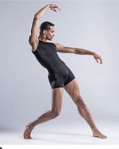 a man in a black leotard is posing with his arms out and legs spread