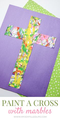 a cross made out of construction paper on top of purple paper with the words paint a cross with marbles