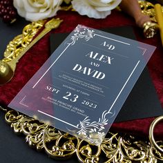 an elegant wedding card is displayed on a red velvet tablecloth with gold trimmings