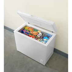 a small chest freezer sitting on the floor next to a wall with food in it