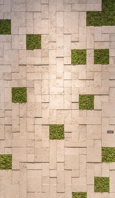 a white and green tiled wall with grass growing on the tiles in it's center