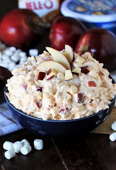 a bowl filled with oatmeal next to apples and marshmallows