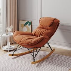 an orange rocking chair sitting on top of a rug in front of a white wall