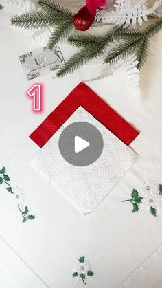 a white table cloth with red and green designs on it, surrounded by christmas decorations