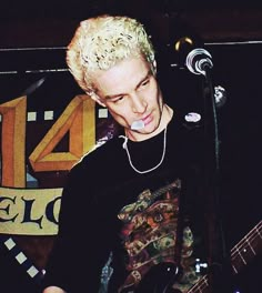 a young man with blonde hair playing an electric guitar