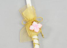 a white pen with a pink flower on it and a gold ribbon around the tip