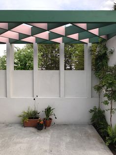 an outdoor patio area with potted plants on the concrete and green awnings