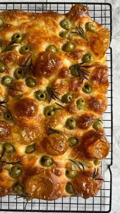 olive bread on a cooling rack with rosemary sprigs and olives in the crust