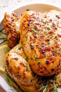 a close up of a chicken on a plate with lemon wedges and garnish