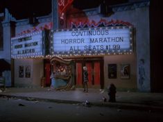 the marquee is lit up at night and people are standing in front of it