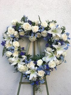 a wreath with white and blue flowers hanging on a wall next to a steplader