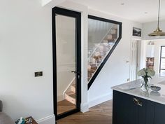 an open door leading to a kitchen and living room area with stairs in the background