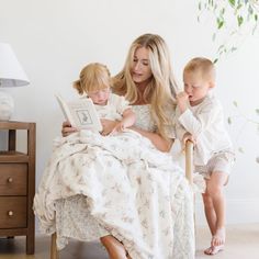 a woman reading to two children while sitting on a bed