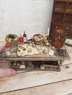 a miniature table with various items on it and a birdcage in the background