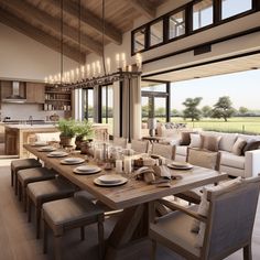 a large open concept kitchen and dining room with wood flooring, wooden ceiling beams, glass windows, beige couches, white chairs