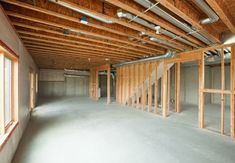 an unfinished room with wood framing and exposed pipes on the ceiling, along with several windows