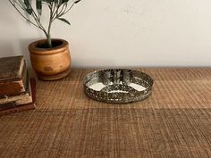 a bowl sitting on top of a table next to a potted plant and books