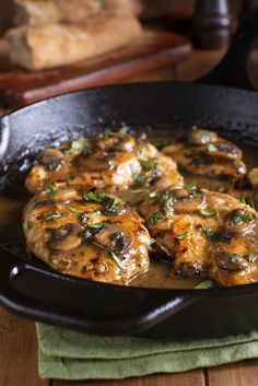 chicken with mushrooms and gravy in a cast iron skillet on a wooden table