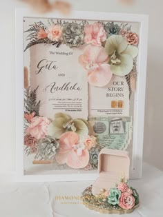 a wedding card with flowers on it next to a ring box and other items for the bride's bouquet