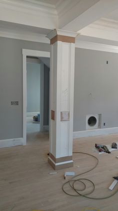 an unfinished room with wood flooring and white pillars in the middle, being worked on