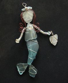 a glass figurine that is sitting on a black surface with beads and wire