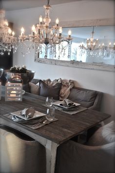 a dining room table with place settings and chandelier hanging from the ceiling above it