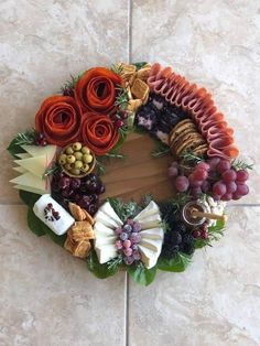 a wreath made out of fruits, vegetables and meats on a tile floor in front of a wall