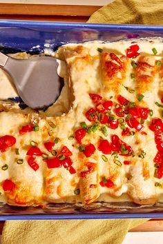 a casserole dish with cheese, tomatoes and green onions