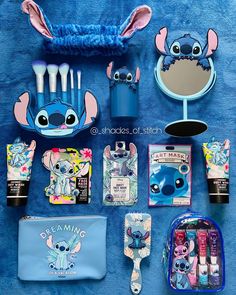 various items are displayed on a blue towel and include toothbrushes, makeup bag, eyeliners, lipstick, mirror, etc