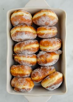 a box filled with lots of sugar covered doughnuts