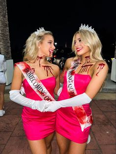 two beautiful women in pink dresses standing next to each other with crowns on their heads