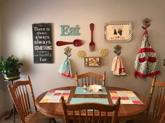 a dining room table with wooden chairs and place mats on the wall above it is decorated with kitchen utensils