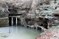 a small pool in the middle of a cliff with water coming from it and some rocks on either side