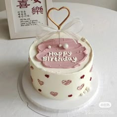 a birthday cake is decorated with hearts and the words happy birthday written in chinese on it