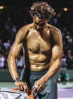 a shirtless male tennis player holding his bag