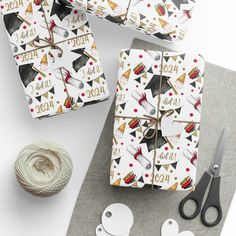 wrapping paper and scissors are sitting on a table next to yarn, twine and crochet hooks