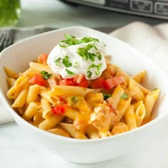 a white bowl filled with pasta covered in sauce and topped with sour cream on top