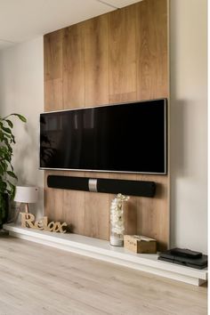 a flat screen tv mounted to the side of a wooden wall in a living room