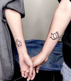 two people holding hands with tattoos on their arms