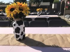 a vase filled with sunflowers sitting on top of a table covered in burlocks