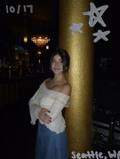 a woman standing next to a tall gold pole