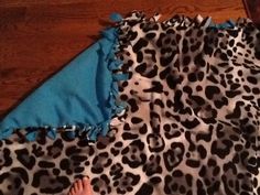 a person laying on top of a leopard print blanket next to a blue and white pillow