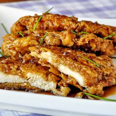 three pieces of fried food on a white plate with some green garnishes