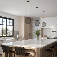 a large kitchen with an island in the middle and three hanging lights on the ceiling